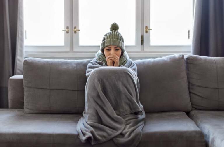 Cold woman at home in blanket