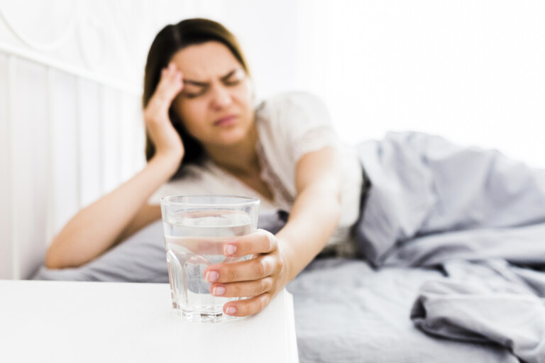 Woman with headache reaches for water