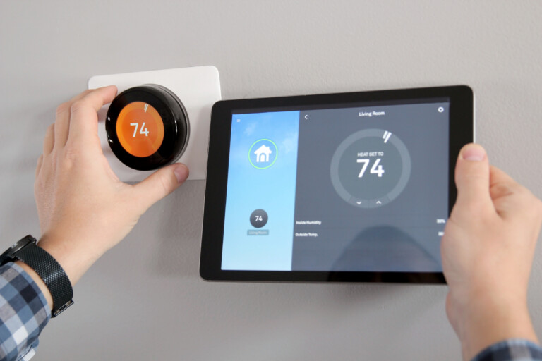 Man is Adjusting a temperature using a tablet with smart home app in modern living room