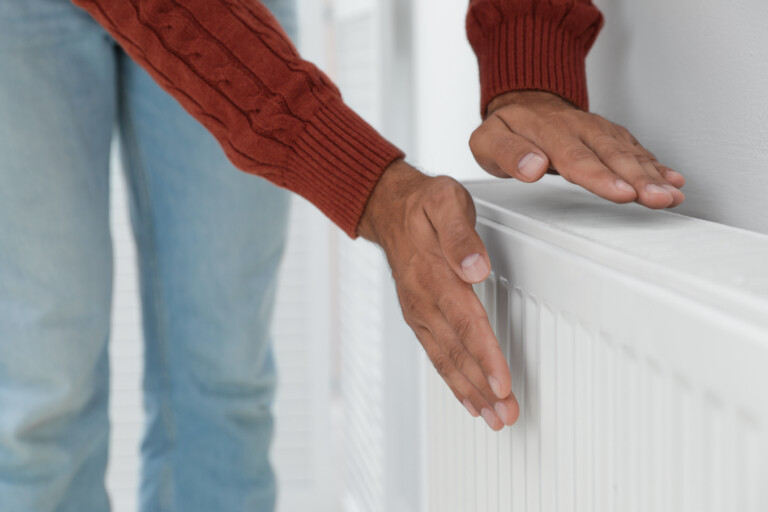 Man warming hands on a radiator