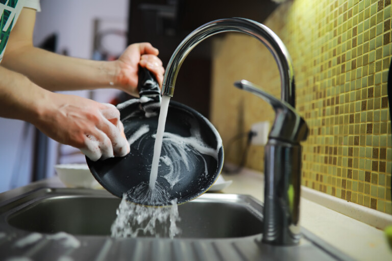 Man washing dishes with hot water